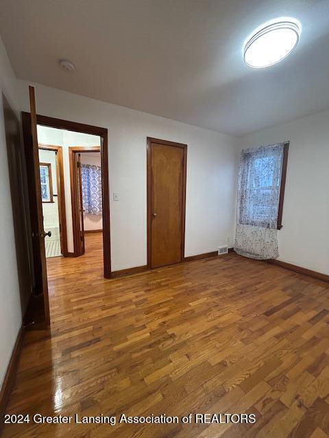 unfurnished bedroom featuring wood finished floors, visible vents, and baseboards