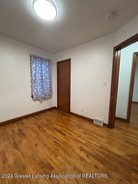 empty room with visible vents, light wood-style flooring, and baseboards