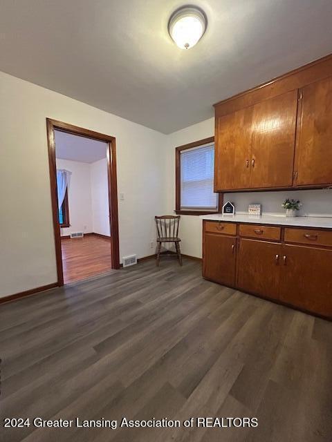 kitchen featuring visible vents, brown cabinets, dark wood-type flooring, and light countertops