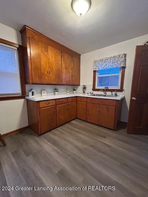 kitchen featuring light countertops, brown cabinetry, a sink, and dark wood-style flooring