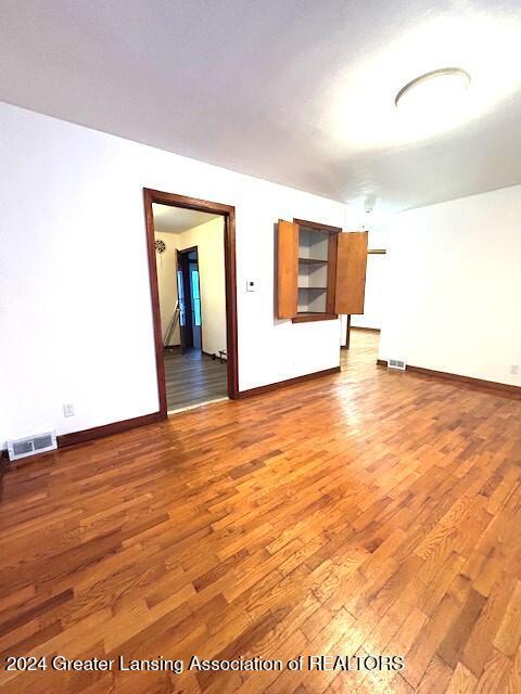 empty room featuring baseboards, visible vents, and light wood finished floors