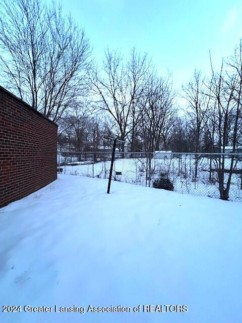 yard covered in snow featuring fence