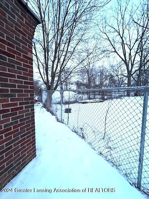 snowy yard featuring fence