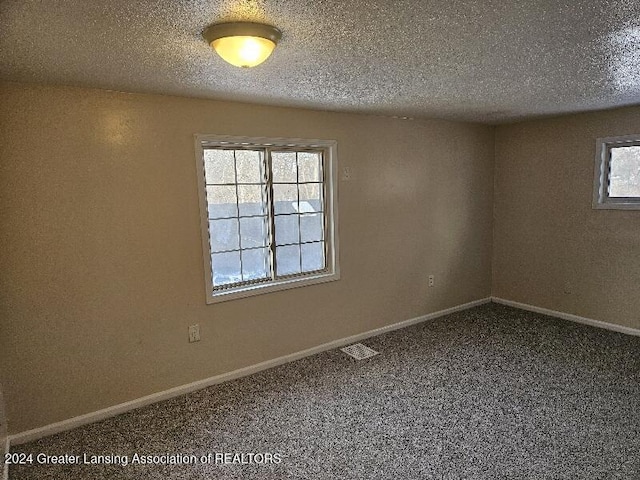 spare room featuring carpet floors and a textured ceiling