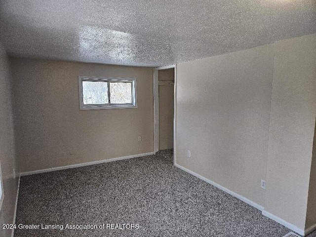 spare room featuring a textured ceiling and carpet flooring