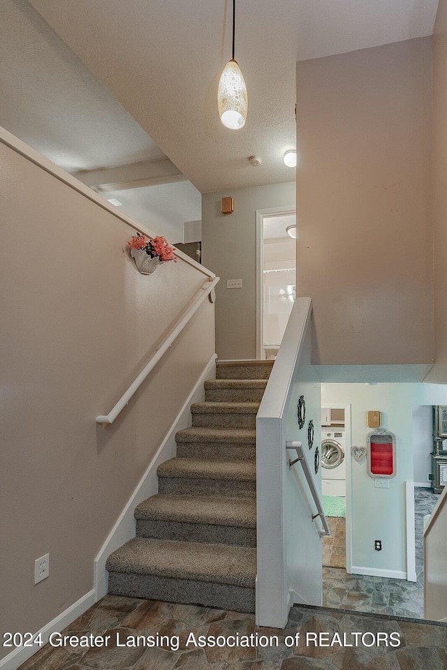 stairway with hardwood / wood-style flooring, a textured ceiling, and washer / dryer