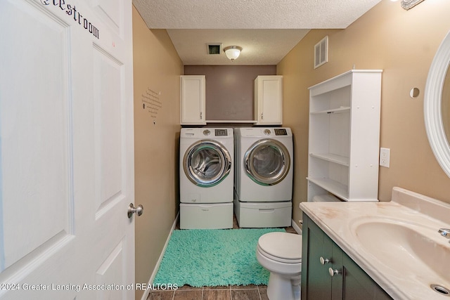 laundry room featuring washer and dryer, sink, and a textured ceiling