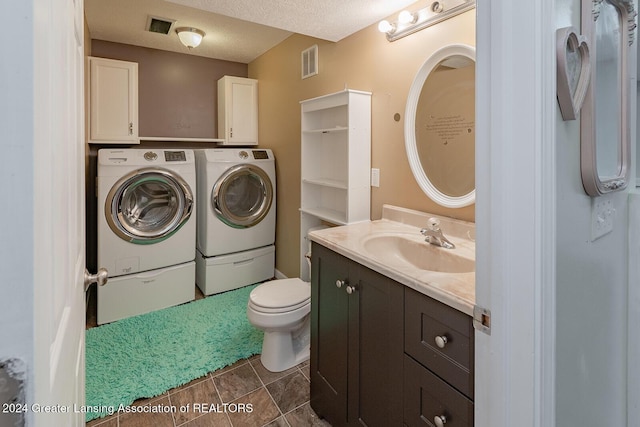 bathroom with a textured ceiling, washer and clothes dryer, vanity, and toilet