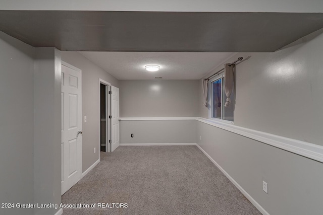 basement with a textured ceiling and light colored carpet