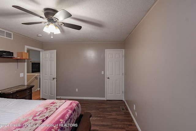 bedroom with a textured ceiling, ceiling fan, and dark hardwood / wood-style flooring