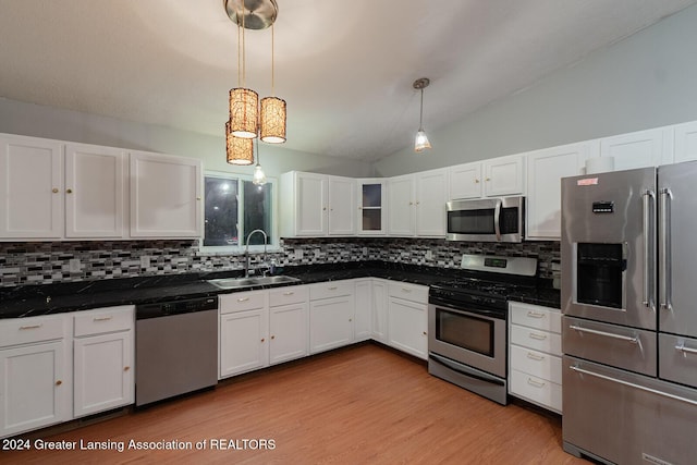 kitchen featuring decorative light fixtures, lofted ceiling, sink, appliances with stainless steel finishes, and white cabinets