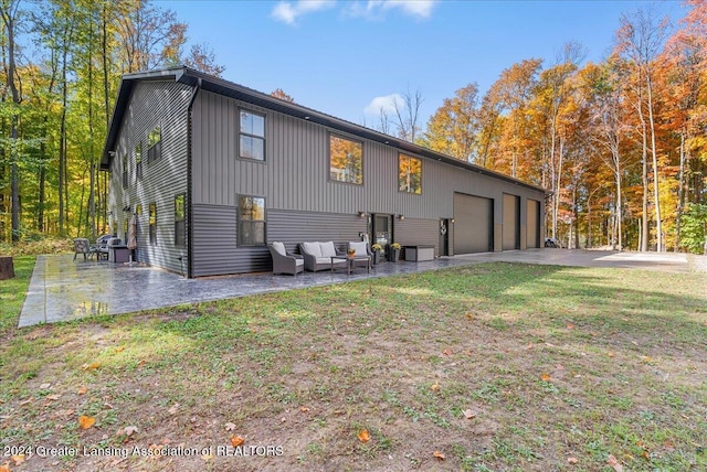 back of property with a garage, a patio area, an outdoor living space, and a lawn