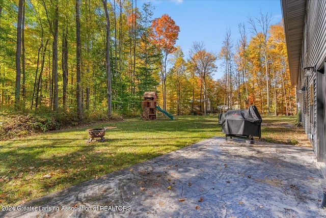 view of yard featuring an outdoor fire pit, a playground, and a patio area