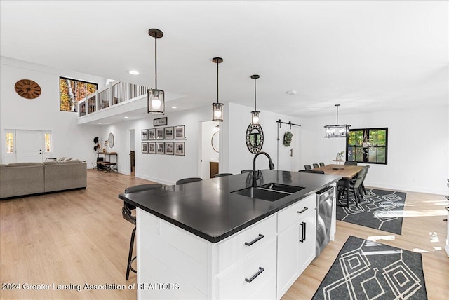 kitchen with sink, white cabinets, dishwasher, and an island with sink