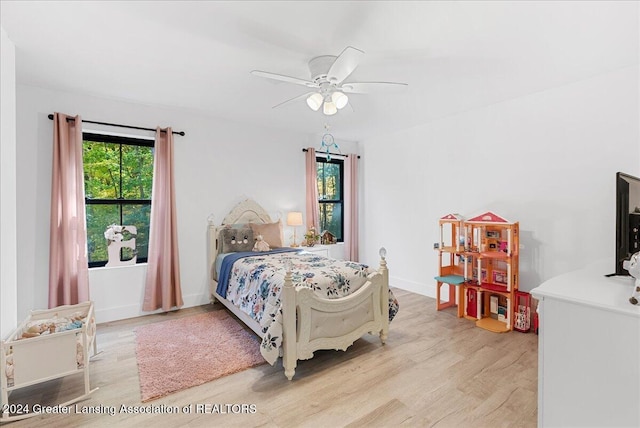 bedroom featuring ceiling fan, multiple windows, and light wood-type flooring