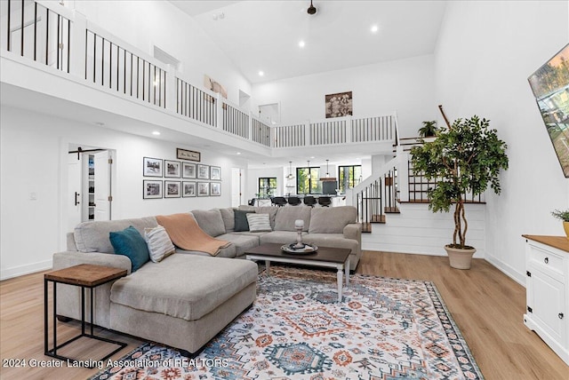 living room with a towering ceiling and light wood-type flooring