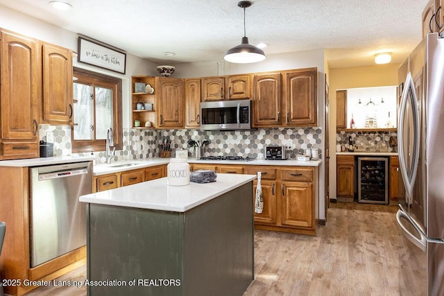 kitchen with wine cooler, sink, decorative light fixtures, a center island, and stainless steel appliances