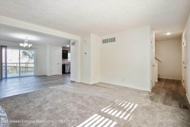 unfurnished living room featuring carpet flooring, a textured ceiling, and a notable chandelier