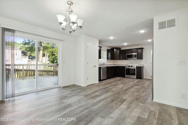 kitchen with light hardwood / wood-style flooring, appliances with stainless steel finishes, hanging light fixtures, dark brown cabinets, and a chandelier