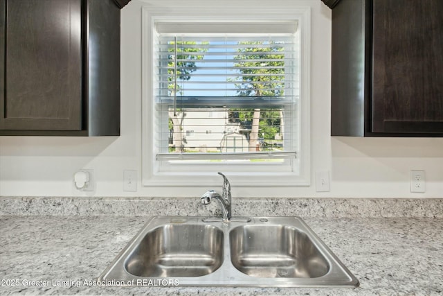 details featuring light stone counters, sink, and dark brown cabinets