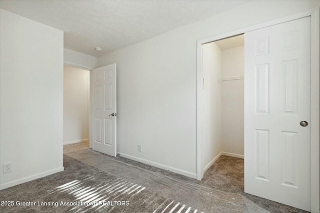 unfurnished bedroom featuring dark carpet, a spacious closet, and a closet