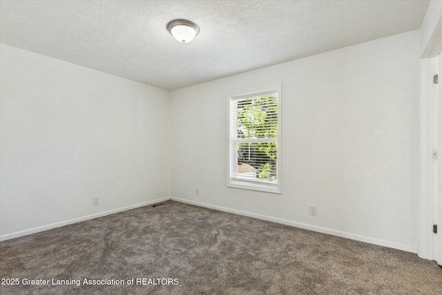 empty room with a textured ceiling and dark colored carpet