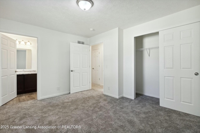 unfurnished bedroom with connected bathroom, light colored carpet, a closet, and a textured ceiling