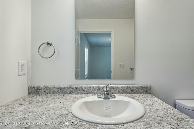 bathroom with vanity, toilet, and a textured ceiling