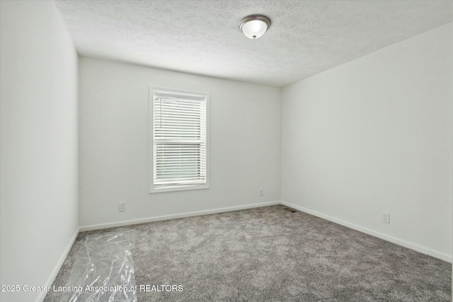 carpeted empty room featuring a textured ceiling