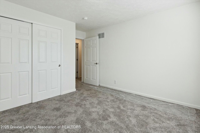 unfurnished bedroom featuring carpet, a textured ceiling, and a closet