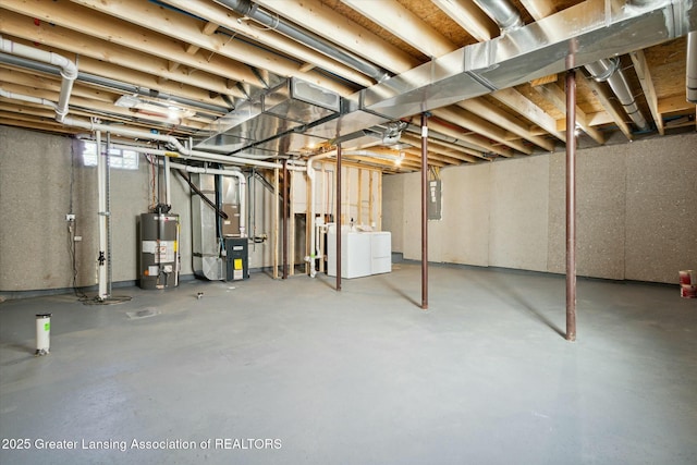 basement featuring heating unit, washer and clothes dryer, electric panel, and water heater