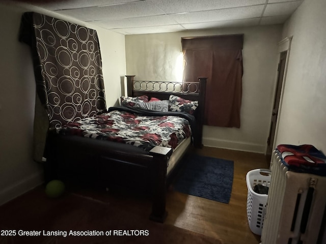 bedroom with a drop ceiling, baseboards, and wood finished floors