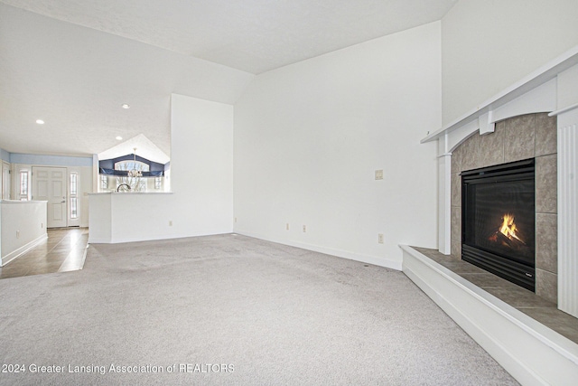 unfurnished living room featuring carpet flooring, a tile fireplace, and lofted ceiling