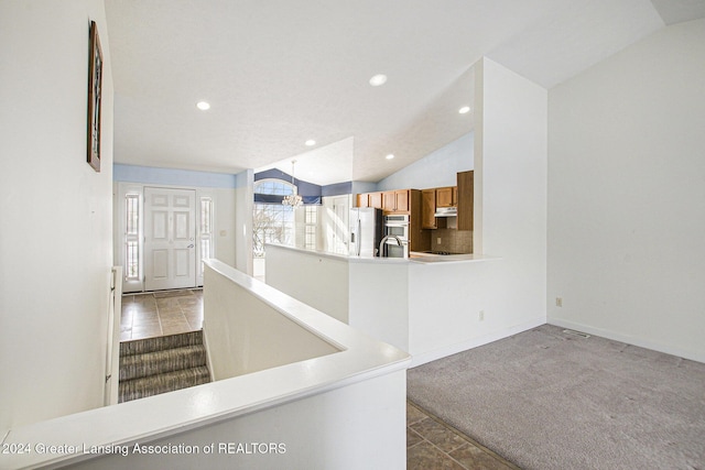 kitchen featuring carpet, lofted ceiling, stainless steel refrigerator with ice dispenser, sink, and a chandelier