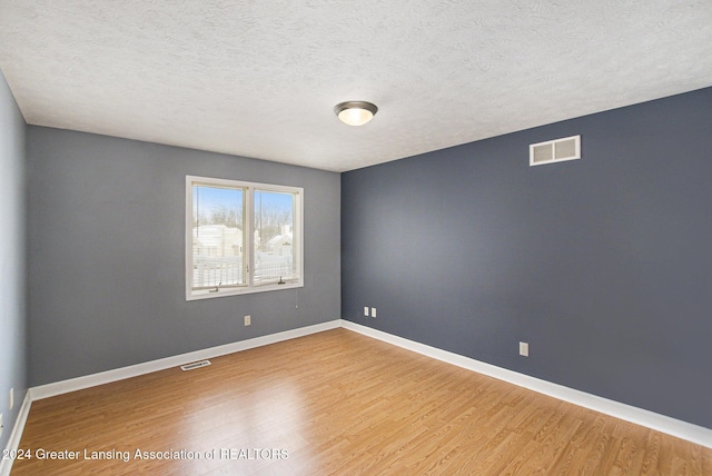 spare room with hardwood / wood-style floors and a textured ceiling