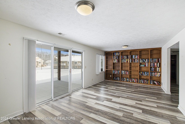 unfurnished room with a textured ceiling and wood-type flooring