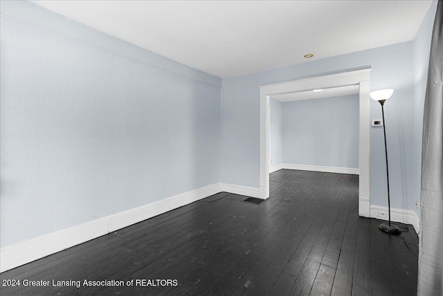 unfurnished room with dark wood-type flooring