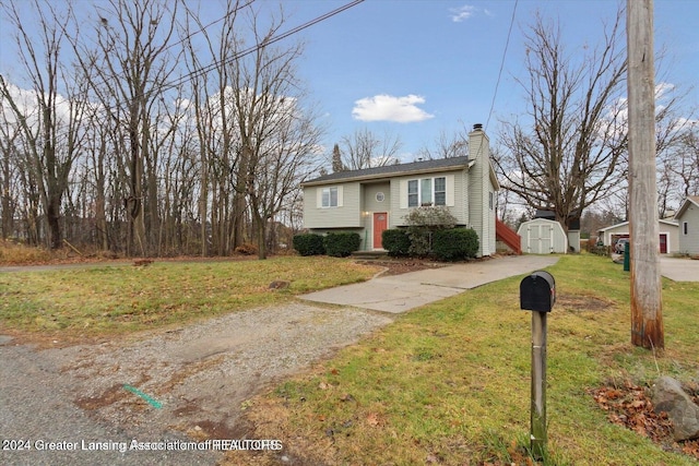 split foyer home featuring a front yard and a storage shed