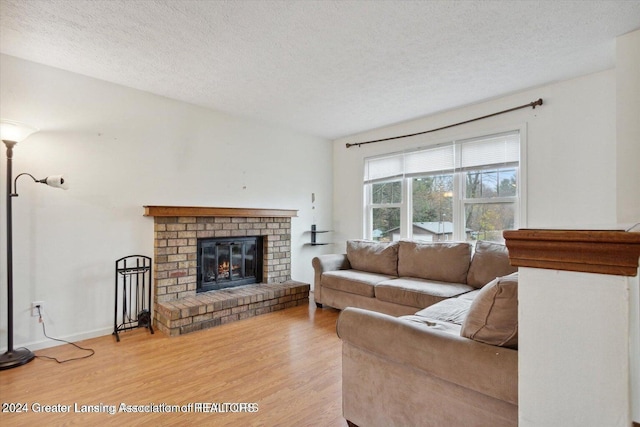 living room featuring light wood-type flooring, a fireplace, and a textured ceiling