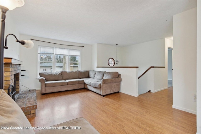 living room featuring light hardwood / wood-style floors, a textured ceiling, and a brick fireplace