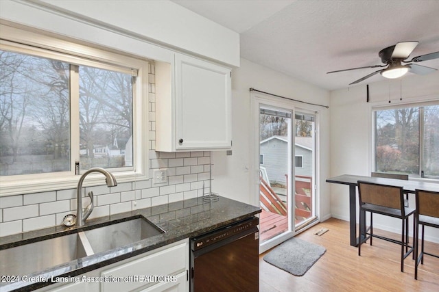 kitchen with dishwasher, white cabinetry, sink, dark stone countertops, and backsplash