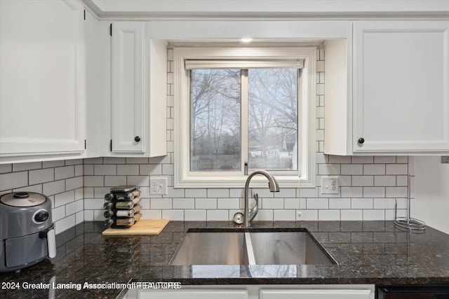 kitchen with sink, backsplash, white cabinetry, and dark stone counters