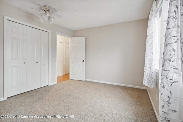 unfurnished bedroom with a closet, ceiling fan, carpet flooring, and a textured ceiling