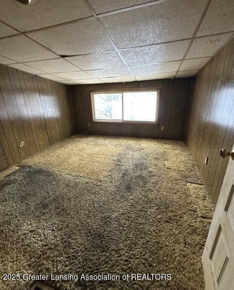 carpeted empty room with wooden walls