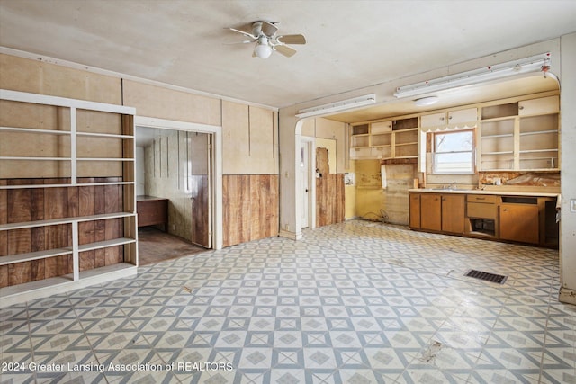 kitchen with sink, ceiling fan, and wood walls