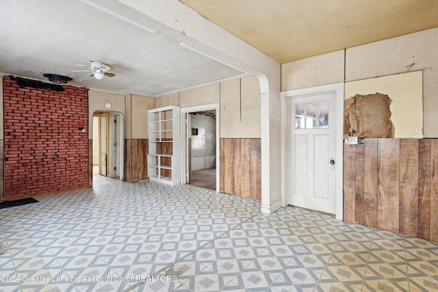 entryway with wooden walls and ceiling fan