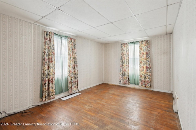 unfurnished room with a paneled ceiling and wood-type flooring