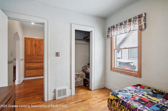 bedroom featuring a walk in closet, a closet, and light hardwood / wood-style flooring