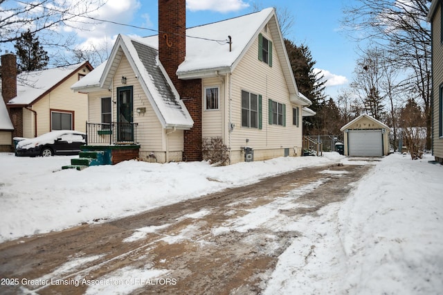 snow covered property with an outbuilding and a garage