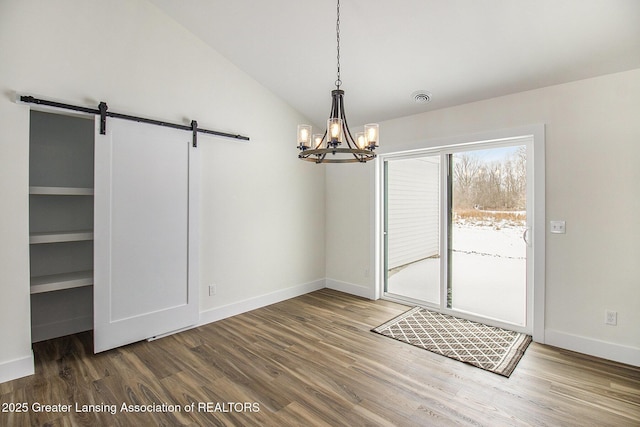 unfurnished dining area with hardwood / wood-style flooring, a barn door, and lofted ceiling